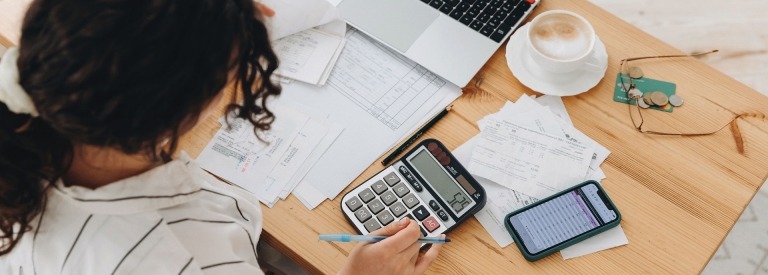 Bovenaanzicht van een vrouw die thuis in de keuken werkt met financiƫle papieren