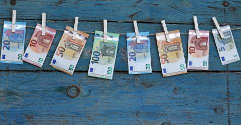 Verschillende euro biljetten hangen aan een waslijn met wasknijpers